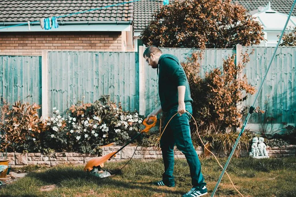 Gardener mowing a lawn in a back garden